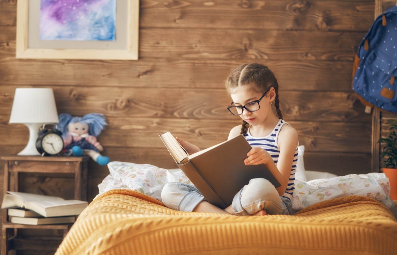 Young girl reading a book wearing eyeglasses